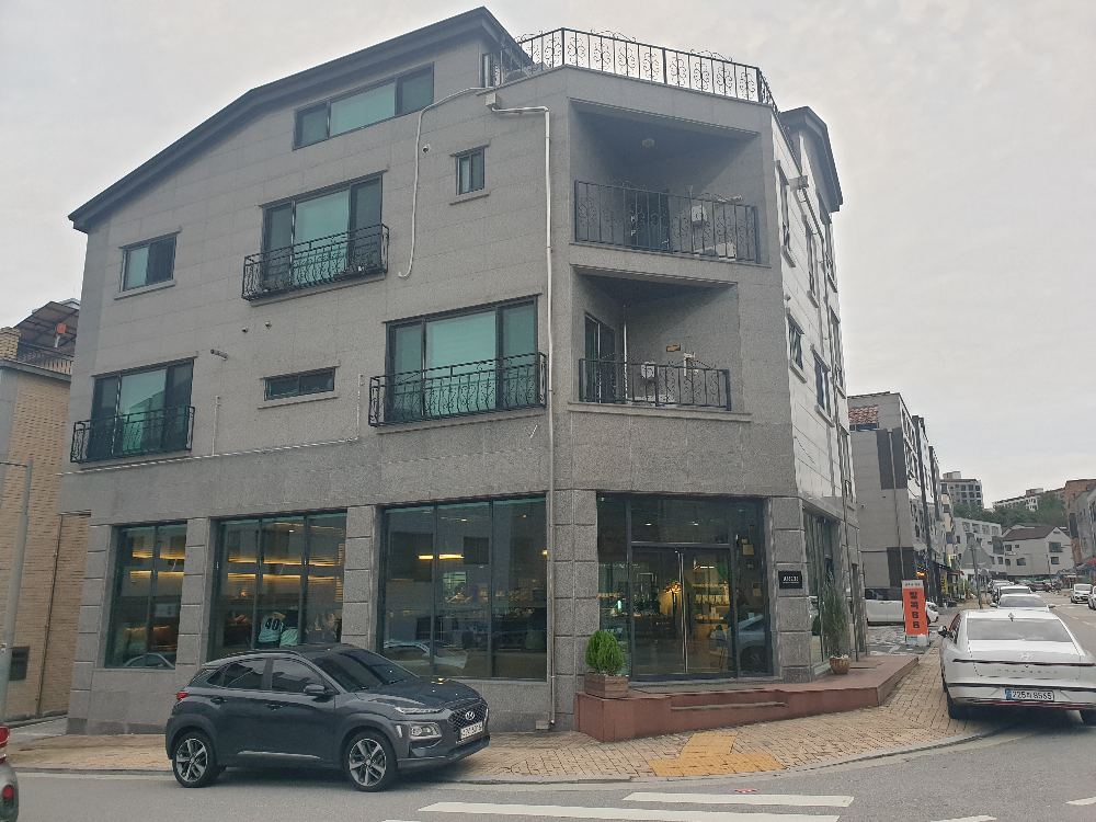 회색 외관의 카페 건물, 1층이 카페다. 내부가 어둡게 보인다.