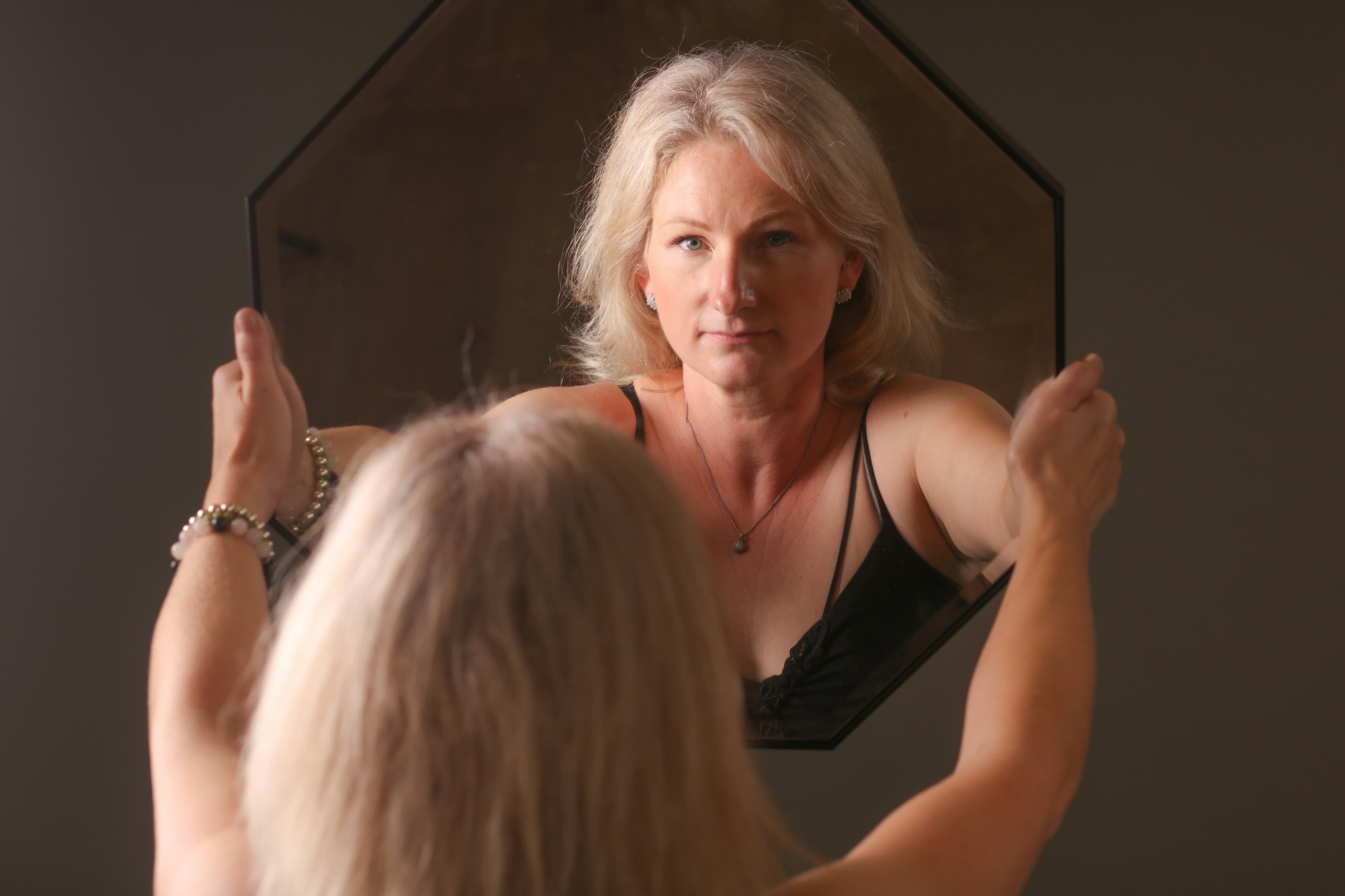 거울 속 자신의 모습을 바라보며 변화를 느끼는 중년 여성, 갱년기와 나이 듦을 상징