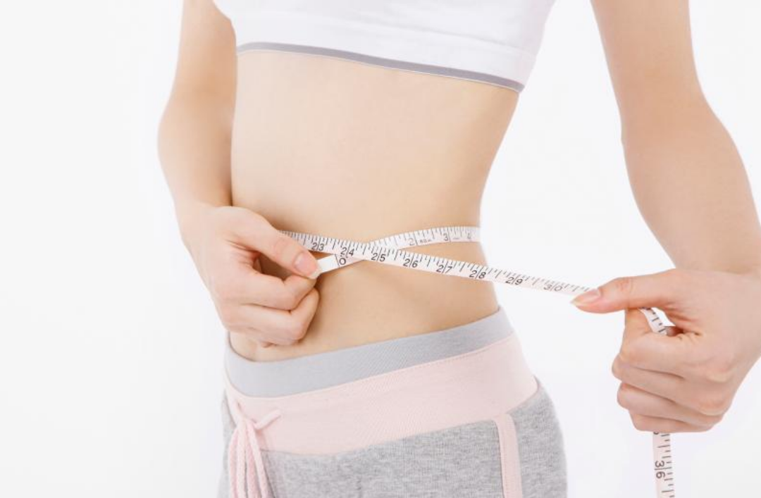 한 여성이 허리 둘레를 재고 있다