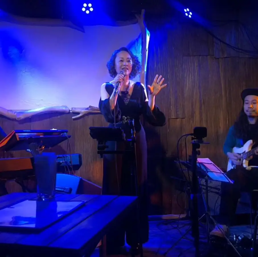 한일-파란조명이 비추는 소무대에서 검은 옷을 입고 마이크를 든채 노래하는 우타고코로 리에