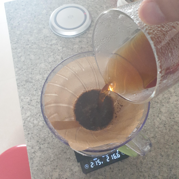 초록색 컵 위에 추출 된 원두가 담긴 드리퍼를 놓고, 추출된 커피를 다시 붓는다.