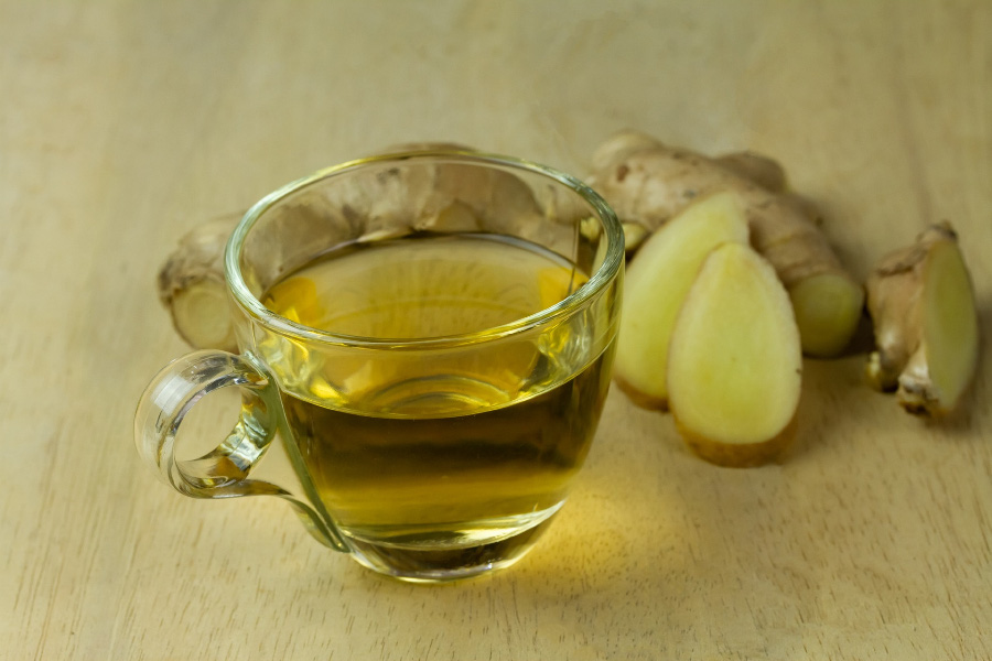 야생에서 채취를 한 생강을 깨끗하게 세척한 후에 마룻바닥 위에 생강 2개와 생강을 썰어 놓은 생강편 3개를 두고, 그 앞에는 생강차를 투명한 찻잔에 가득 담아두고 찍은 사진