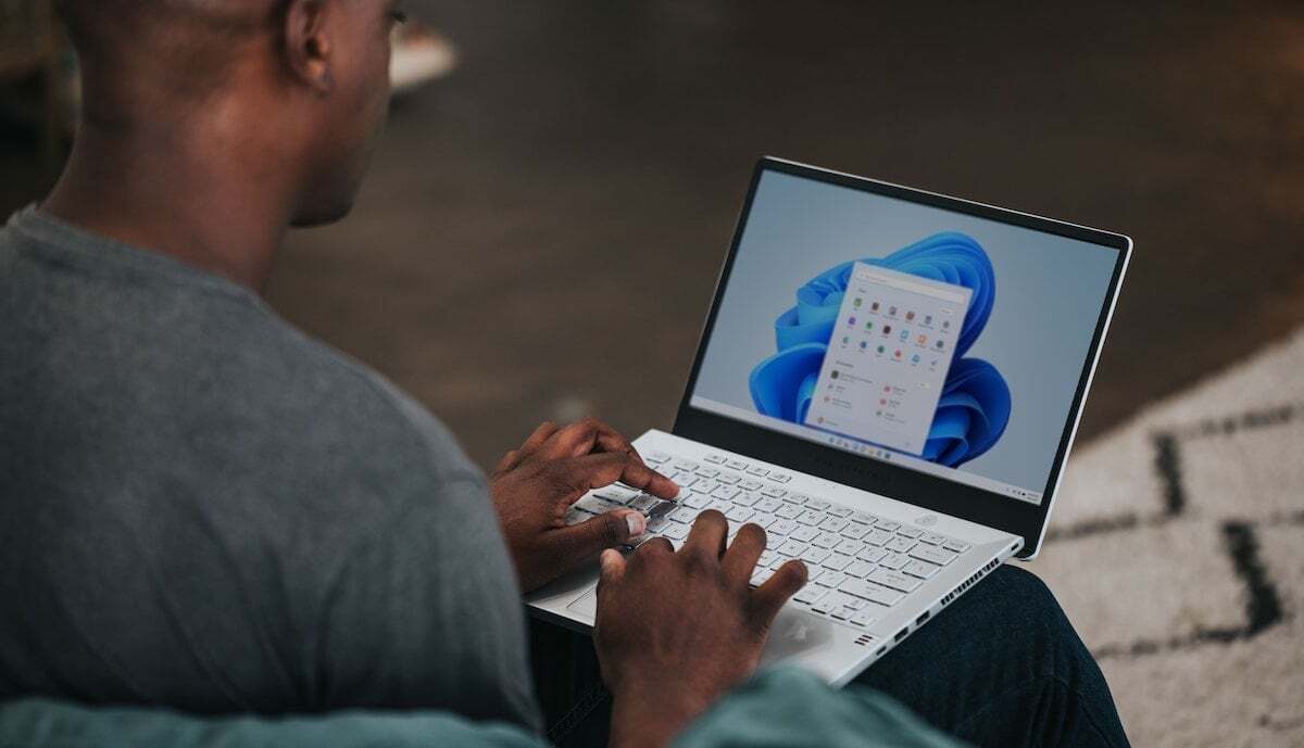 노트북을 무릎에 대고 타이핑하는 남자