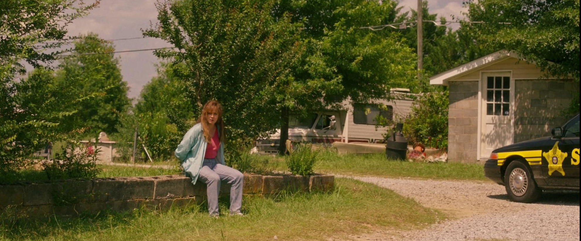 영화 '힐빌리의 노래' 속 시골 마을 도로 옆에 앉아 있는 여주인공과 경찰차