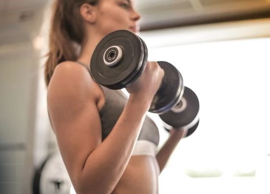 근력운동 매일 해도 되나요 - 여성이 덤벨로 근력운동하는 모습 via canva