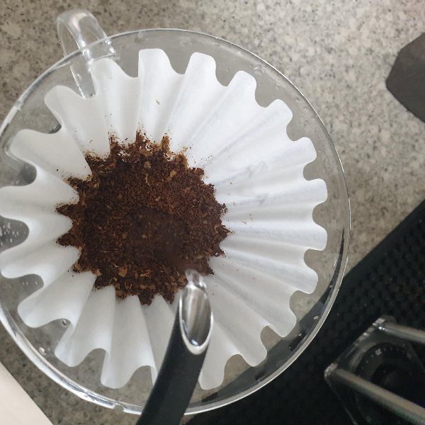 칼리타 웨이브 드리퍼에 필터가 있고 마른 커피파우더가 있다. 뜸 들이기를 시작하려는 중