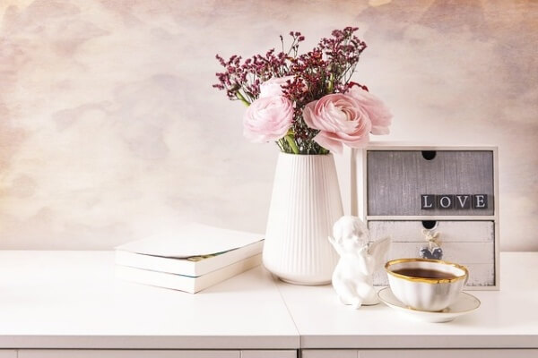 책상 위에 꽃병과 천사인형, 노트가 있는 모습