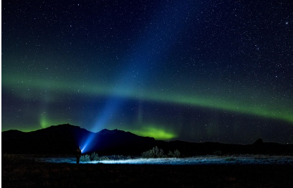 별과 오로라가 보이는 곳에 서있는 한 사람