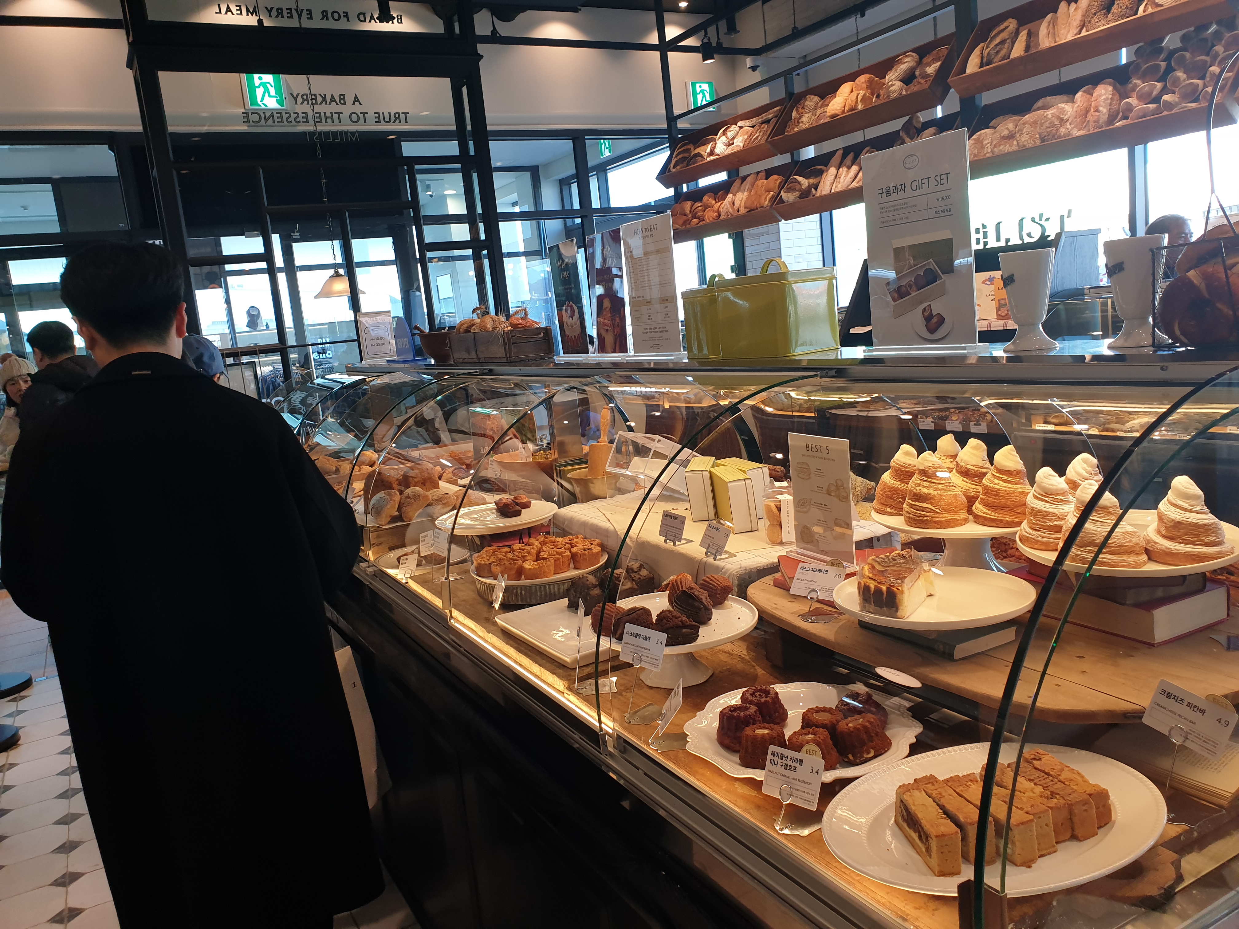 다양한 파운드 케익과 휘낭시에가 진열된 공간을 보고 있는 손님