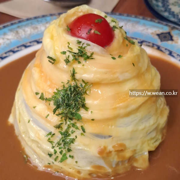 오므라이스 위에 방울토마토가 놓여 있습니다.