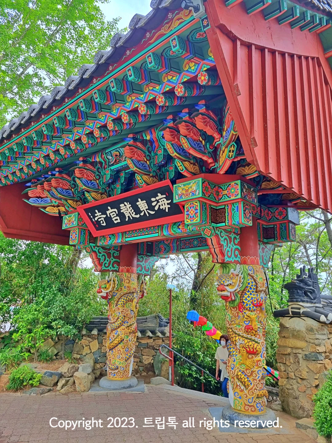 빨간색나무위에 파랑초록등의 화려한 지붕이 있고 기둥엔 용이 장식된 해동용궁사 문이다