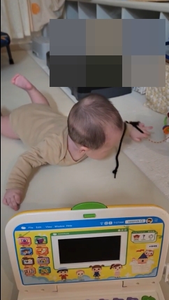 생후 6개월 아기가 터미타임 중 장난감을 향해 배밀이를 연습하는 모습