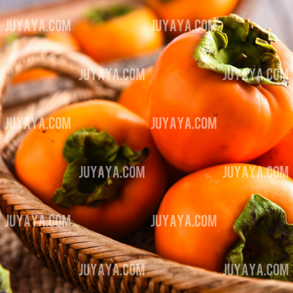 라탄 바구니에 담긴 선명한 주황빛의 감. 면역력을 높이고 피부 건강에 좋은 겨울 제철 과일.