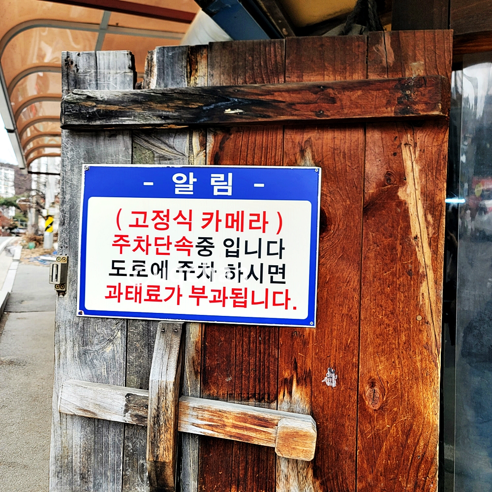 밀밭 칼국수 양주 본점 주의사항으로 고정식 카메라가 잇어 주차 단속중입니다. 도로에 주차하시면 과태료가 부과됩니다. 라고 안내되고 있다.