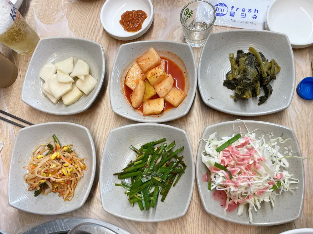 깍두기, 샐러드, 콩나물 등 밑반찬이 접시에 담긴 모습