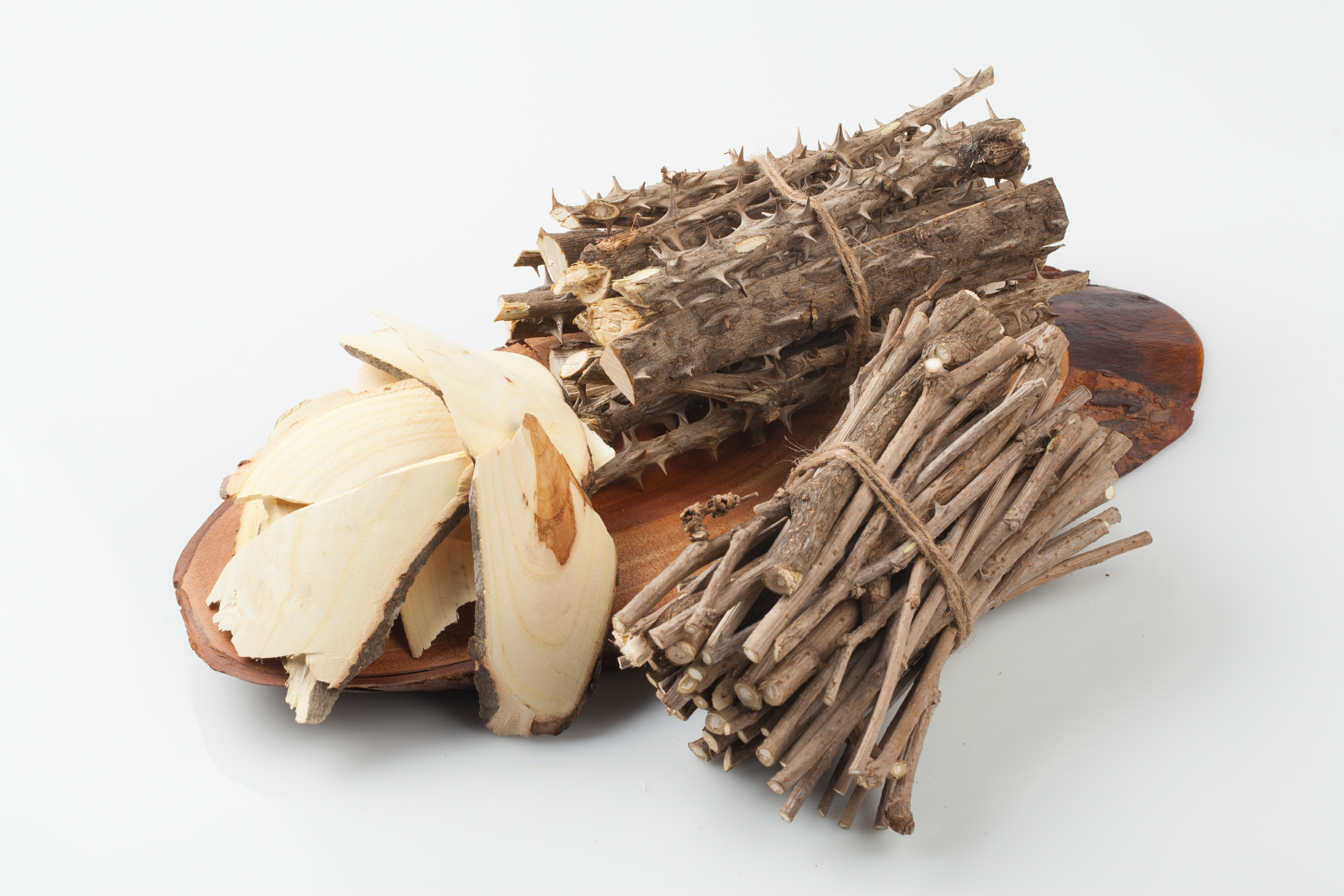 나무로 된 깔판 위에 가시오가피 줄기를 토막 낸 것 한 묶음과 오가피 줄기를 토막 낸 것 한 묶음&#44; 그리고 엄나무를 편으로 잘라 놓은 것을 올려 놓은 사진