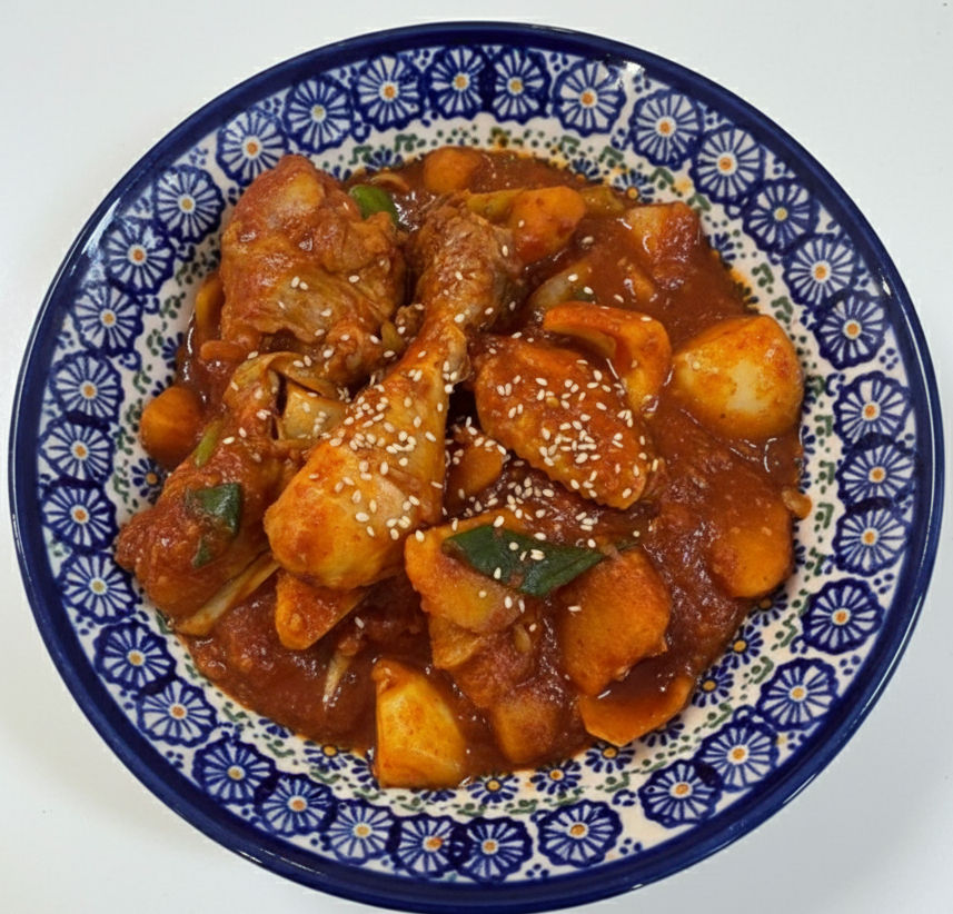 도자기 그릇에 담긴 먹음직스러운 닭볶음탕위에 깨가 뿌려진 모습.