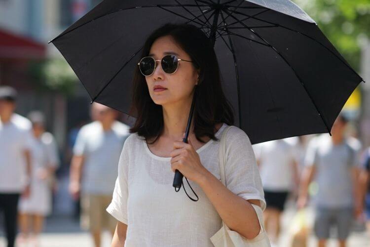 폭염 속 야외에서 선글라스와 양산을 쓴 모습