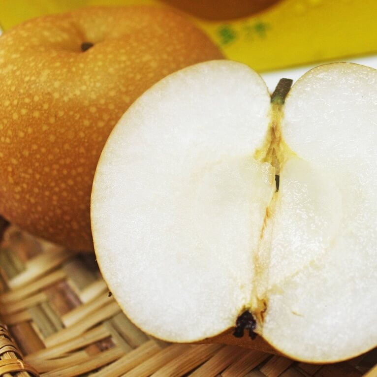 과일 배 한 개와 반쪽으로 잘려진 배가 있는 사진