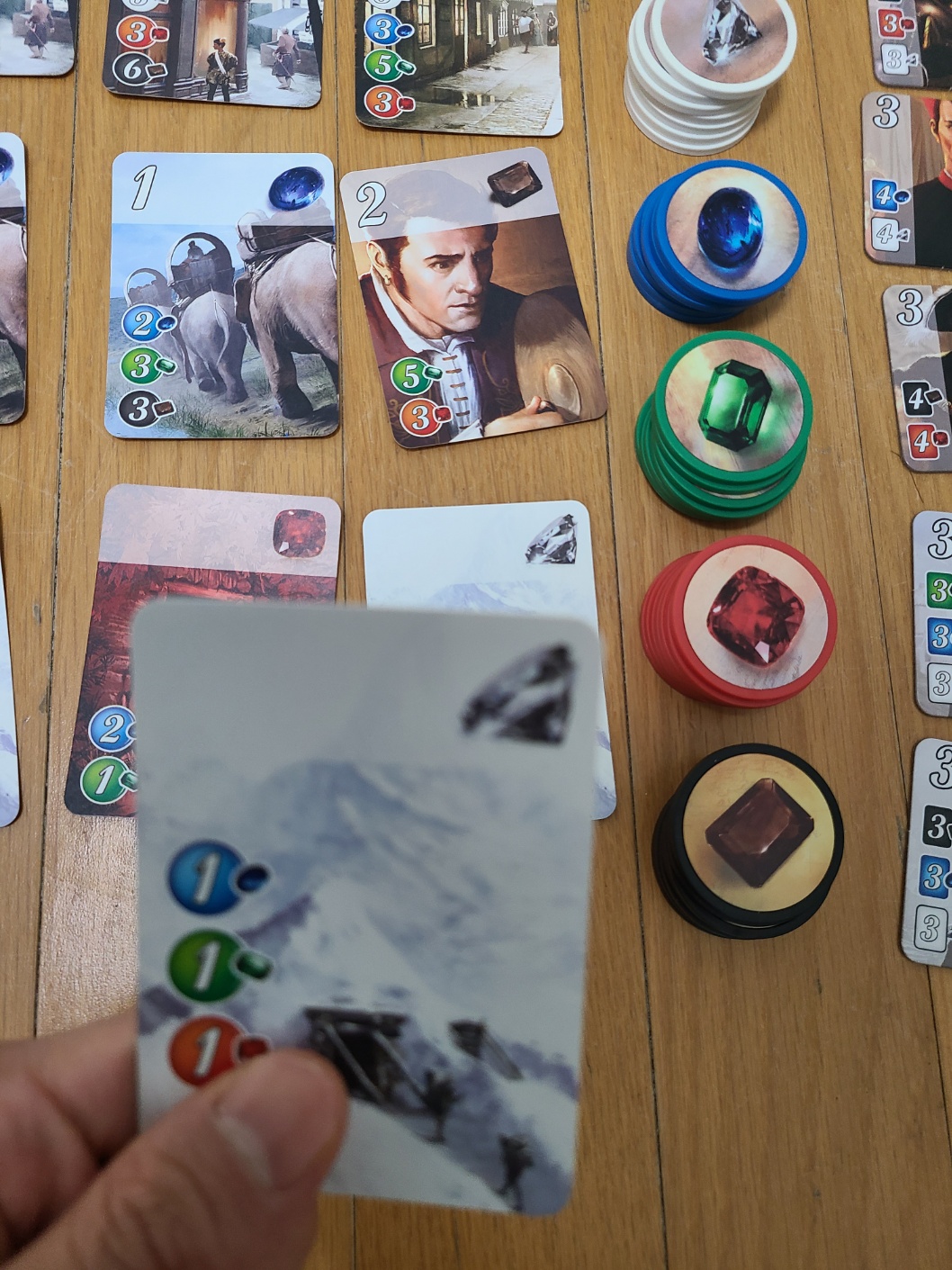 스플렌더 게임에서 전략을 세우는 플레이어의 손과 카드 클로즈업