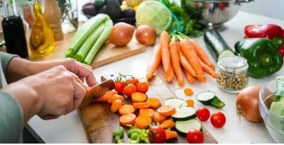 채소가 많이 올려져있는 도마위에 당근을 써는 사진