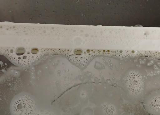 냉장고 선반 프레임 사이 좁은 틈새로 과탄산소다 거품이 보글보글 스며드는 모습