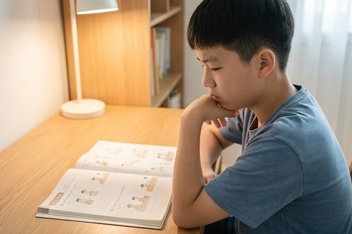 책상에서 턱을 괴고 공부 고민에 잠긴 아들의 모습