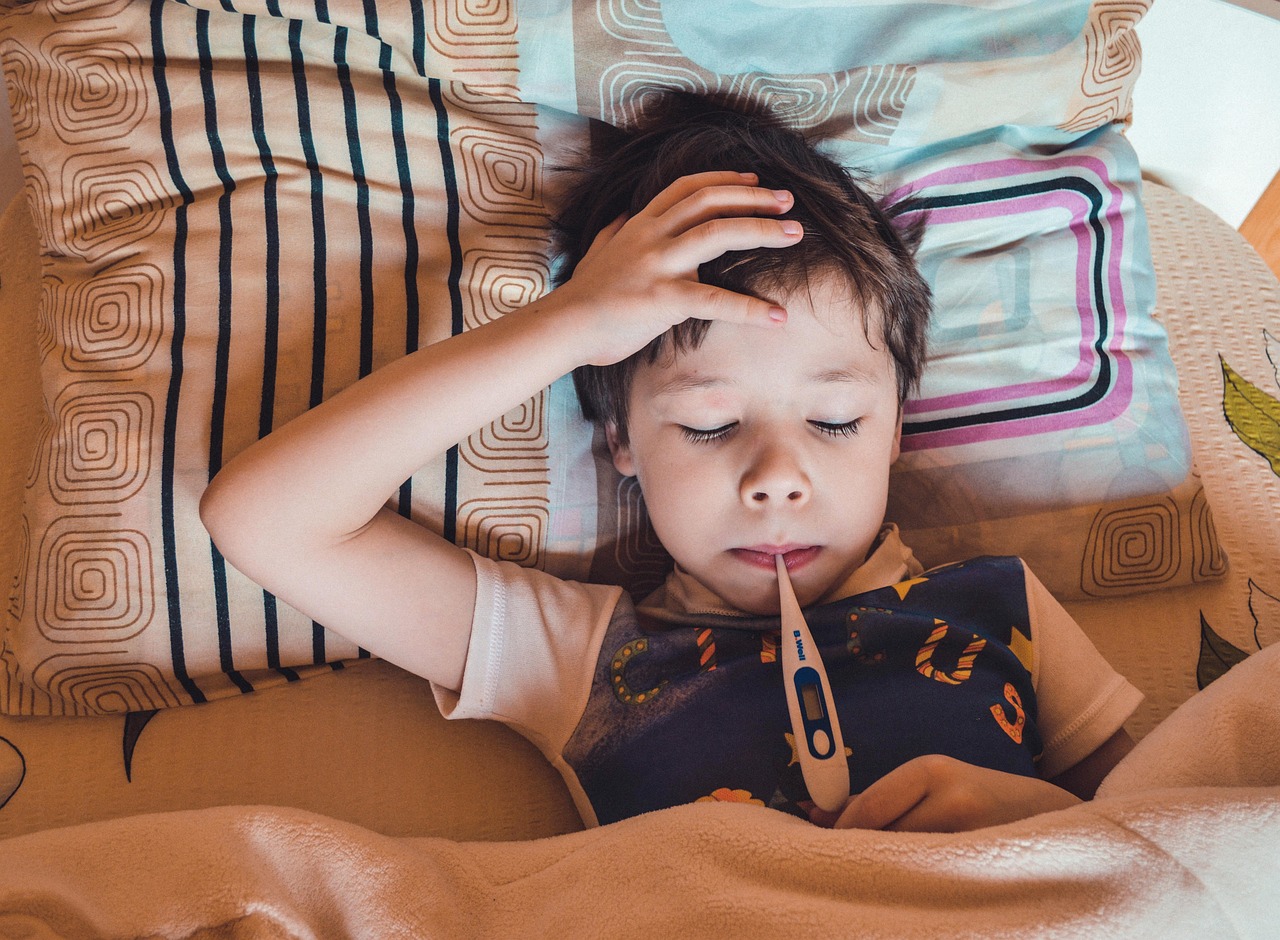 어린아이가 침대에 누워서 열을 재고있음