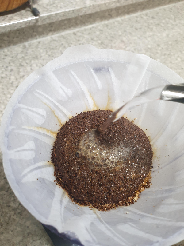 물줄기를 굵게 해서 푸어하는 모습. 드리퍼 안 원두에서 거품이 올라오고 있다.