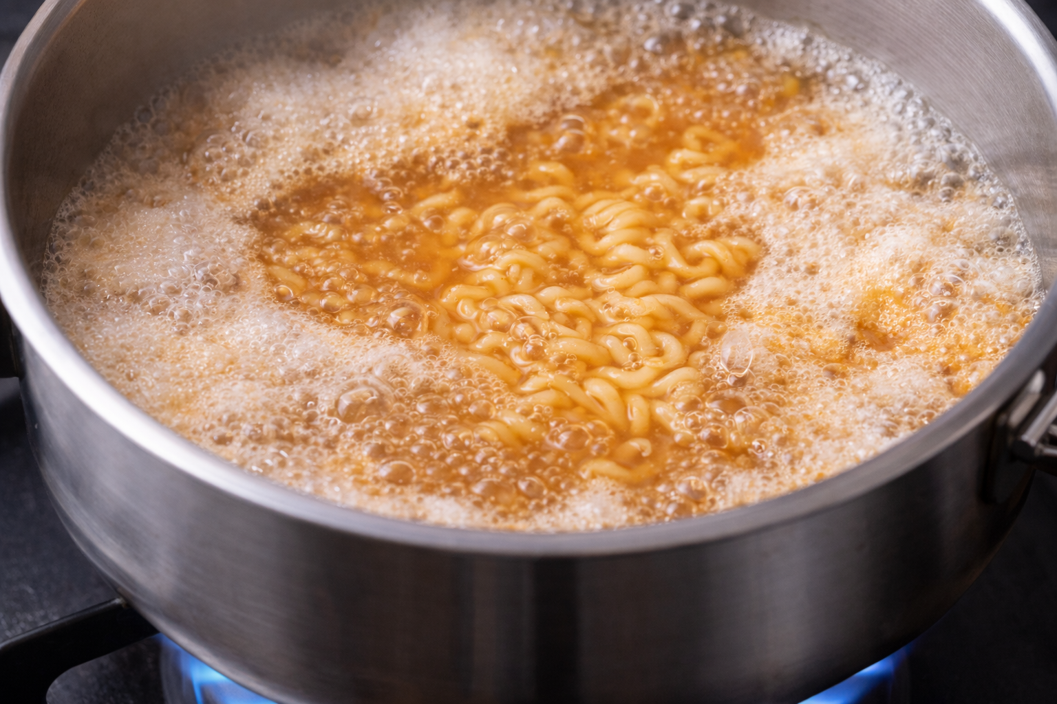 라면이 끓을 때 생기는 거품을 불 조절로 넘치지 않게 관리하는 모습입니다.