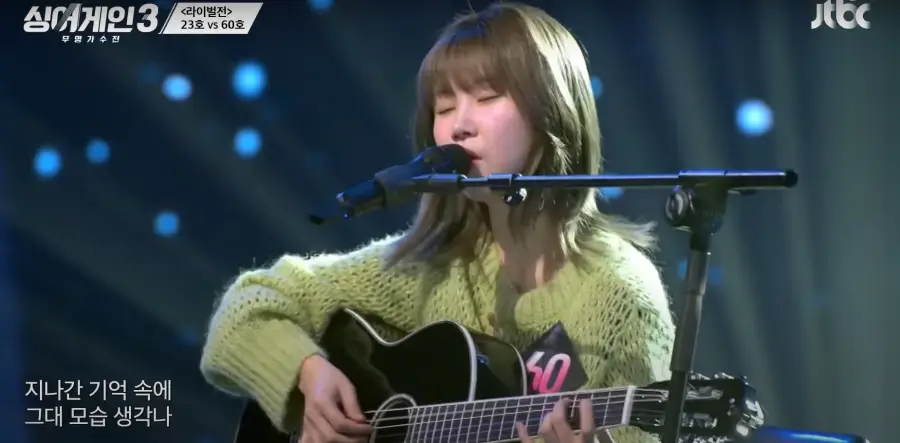 싱어게인 3- 파란색을 배경으로 가슴에 60번호표를 달고 연두색 상의를 입고 단발머리를 늘어뜨린채 두눈감고기타를 치는 60호 상반신