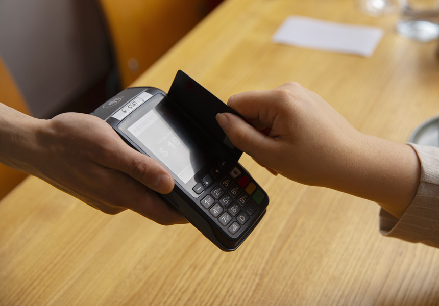 레스토랑에서 신용카드로 계산하는 손의 모습, 결제 단말기에 카드를 대는 장면