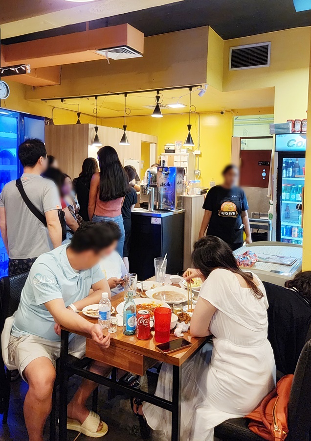 카운터앞 불을선 사람들과 음식을 먹는 사람들