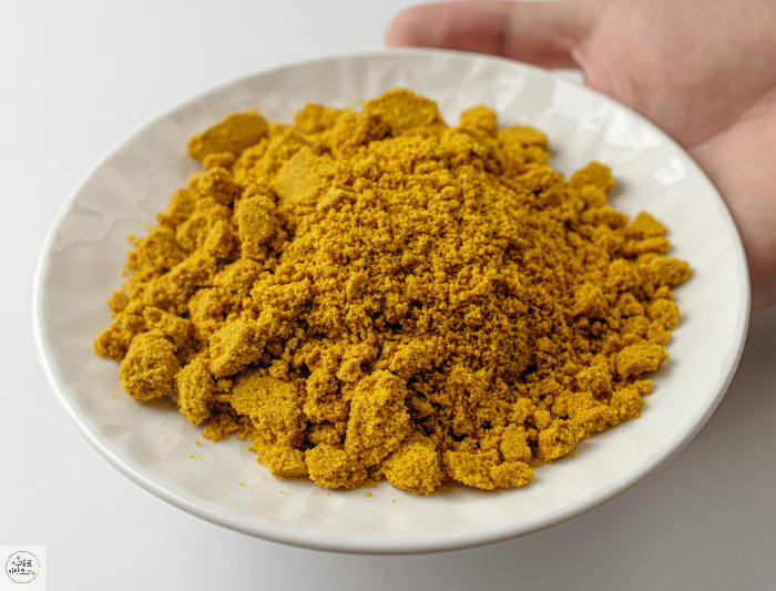 흰접시에 강황가루를 담고 손으로 접시를 들었음