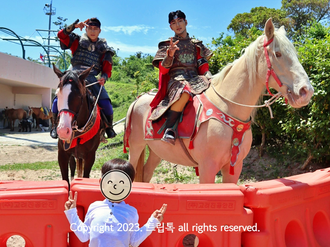 두 출연 몽골 배우가 갈색과 하얀 말위에서 포즈를 취해준다.