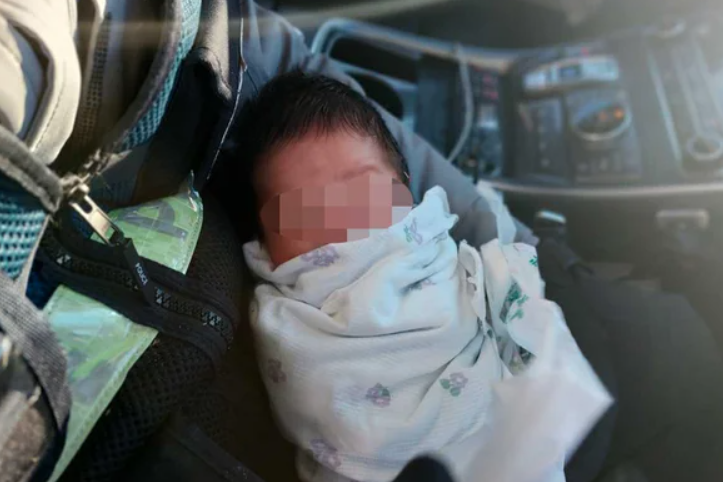 한파 속 버려진 갓난아이가 구조되어 경찰관의 품에 있는 모습