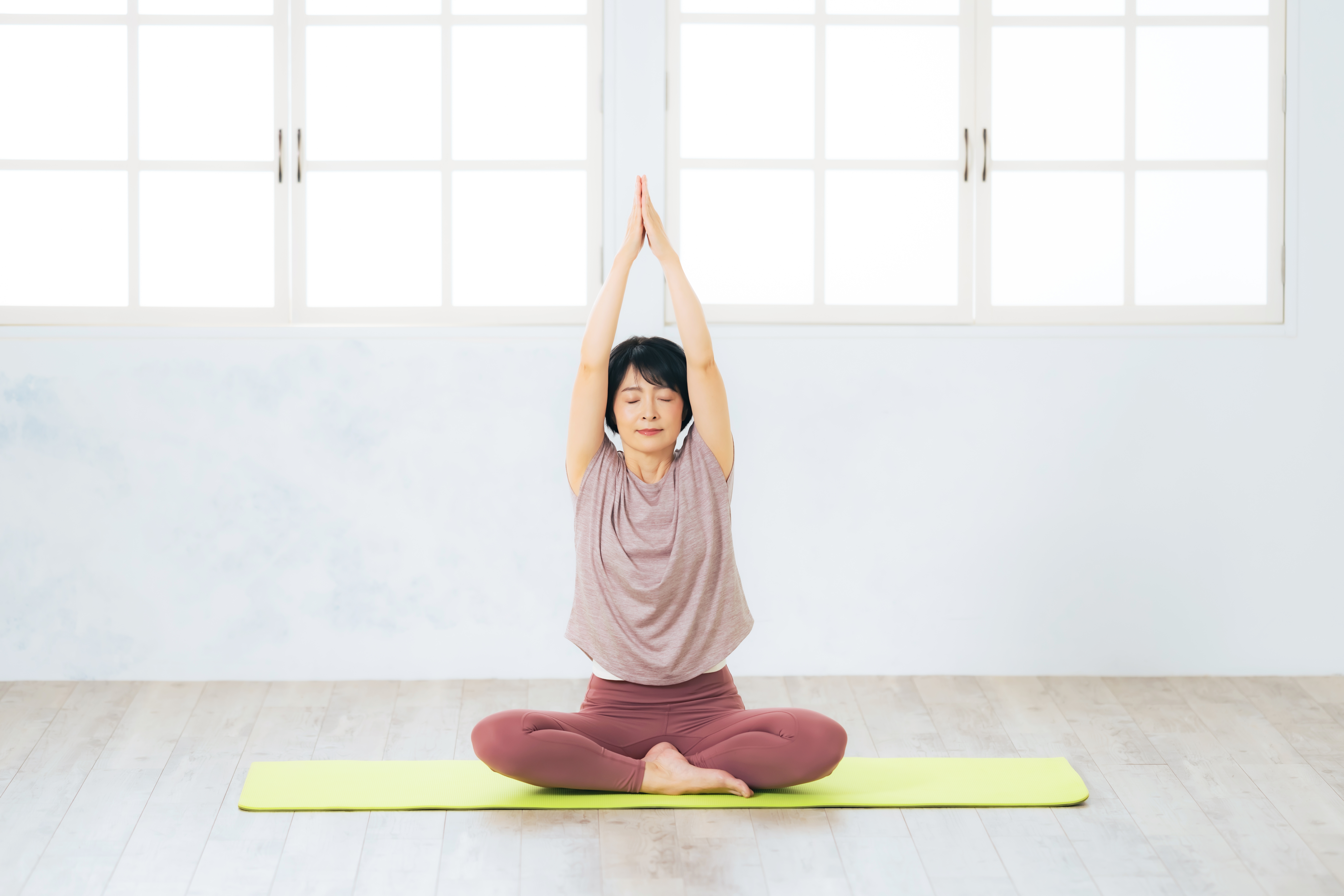 요가 매트 위에서 명상 자세로 스트레칭하는 중년 여성 – 갱년기 여성에게 적합한 유연성 강화 운동을 실천하는 장면