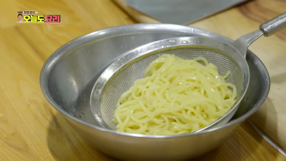삶은 면을 체에 받쳐 헹구는 모습