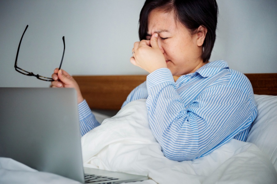 화면 사용으로 지친 눈을 지압하며 안구건조증 증상을 관리하는 중년 여성의 모습
