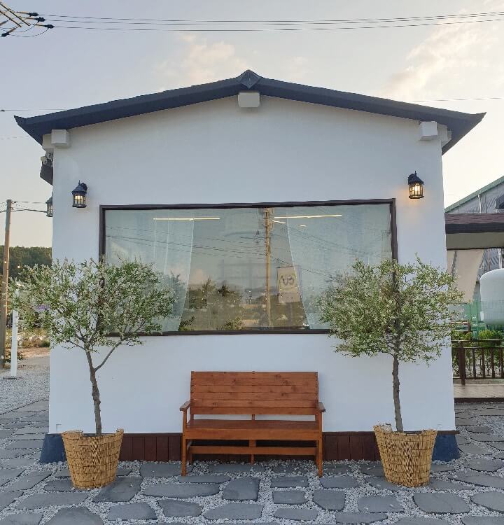 카페서온-포토스팟-한가운데에-벤치가-있고-벤치-양옆엔-나무-두그루가-있다