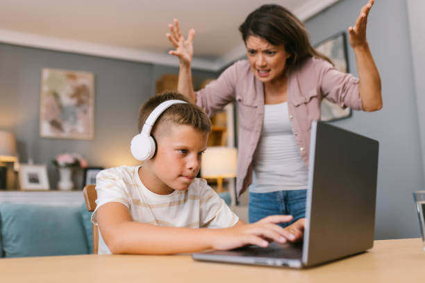 디지털 중독으로 노트북에서 눈을 떼지 못하는 남자아이와 그 모습을 답답하게 쳐다보는 여자