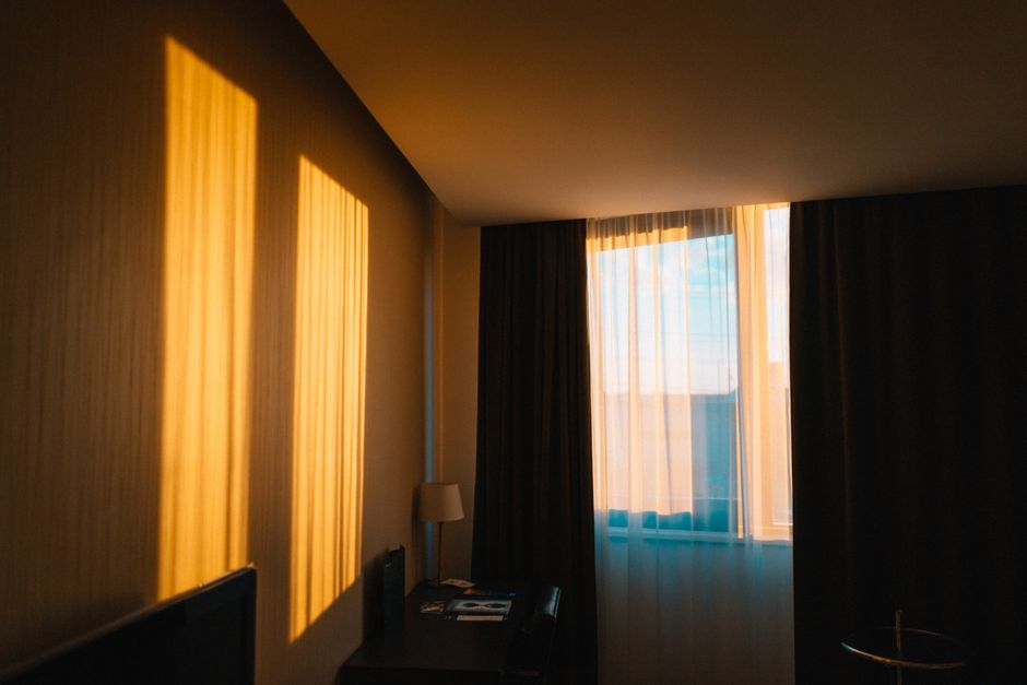 A contemporary hotel room draped in warm morning light casting shadows on the wall.