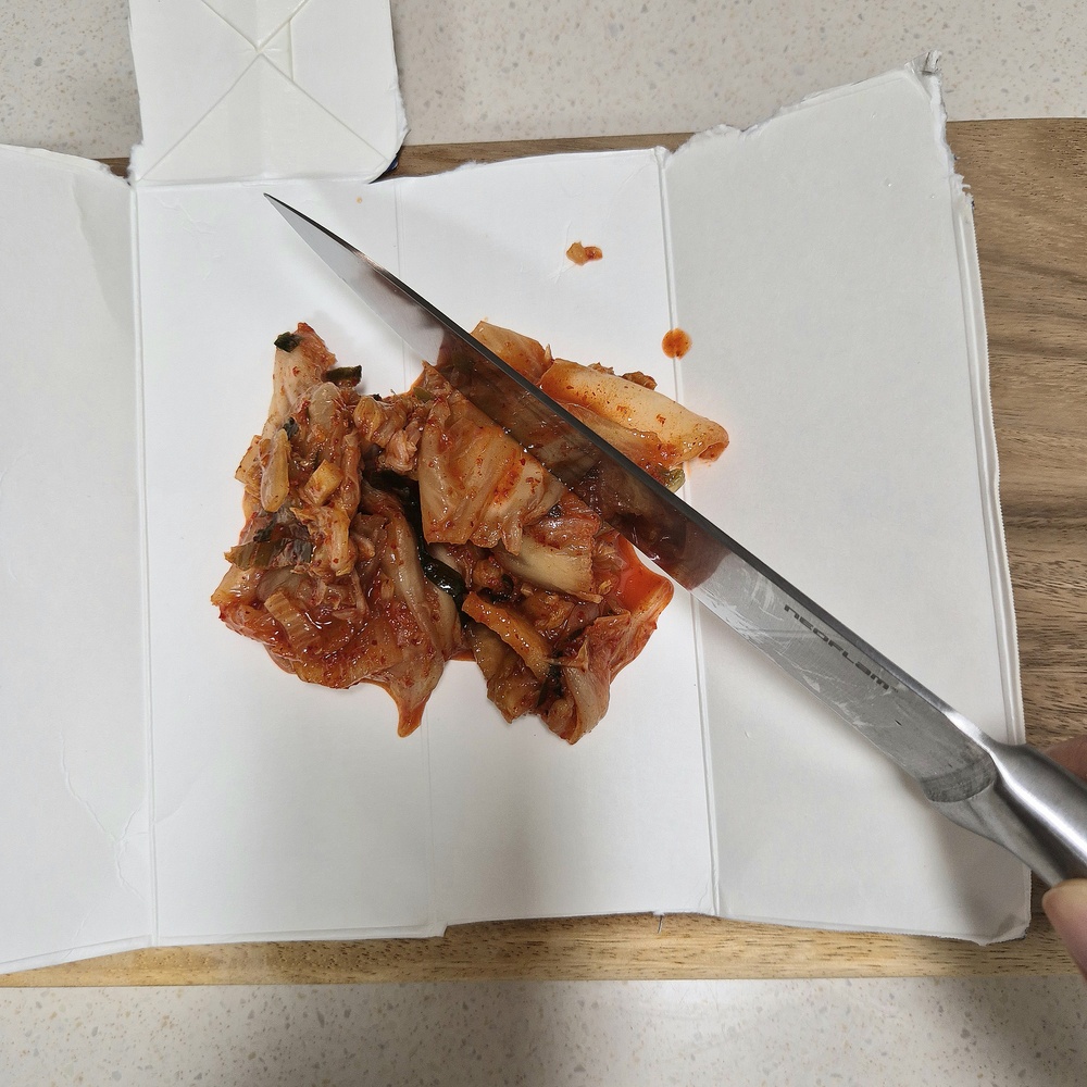 우유팩을 도마 위에 펼쳐 김치를 손질하는 모습