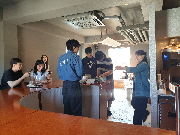 바 테이블에 고객들이 앉아 있고. 카운터에서는 고객이 주문을 하고 있다.