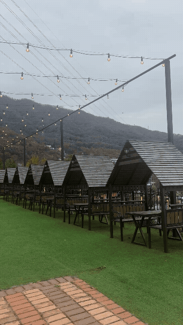 로코스바비큐 야외 바베큐존 훑어보는 동영상 GIF 푸른 잔디밭 위에 캠핑장 느낌의 좌석들이 보인다. 