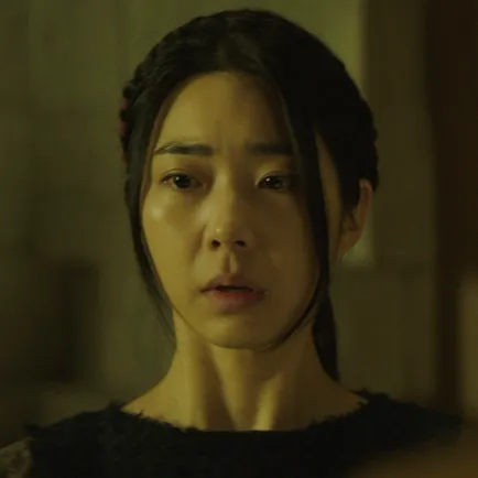 실내를 배경으로 30대 여성이 긴머리를 뒤로 묶고 검은 드레스를 입은 아라문의 검 백하