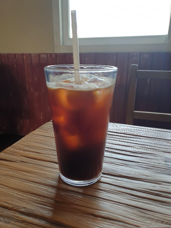 테이블 위에 빨대가 꽃힌 아메리카노가 있다.