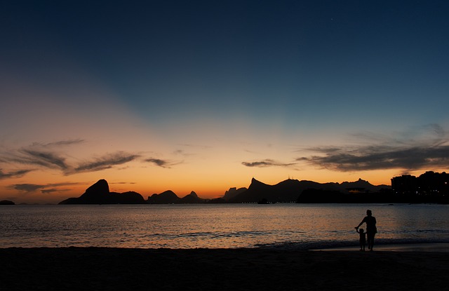 해 가지고 해변에 아이와 어른이 손을 잡고 서있는 사진