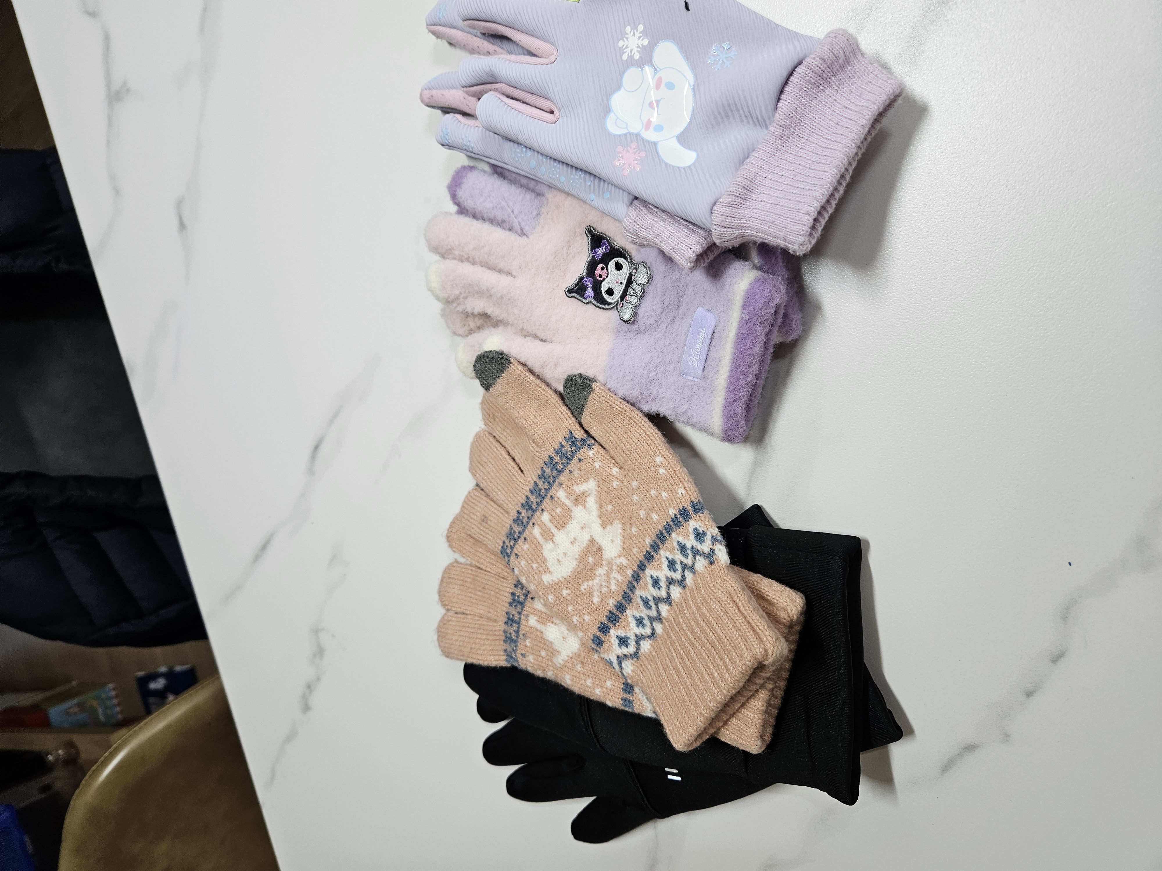 테이블 위에 나란히 놓인 아동용 캐릭터 장갑과 성인용 방한 장갑들