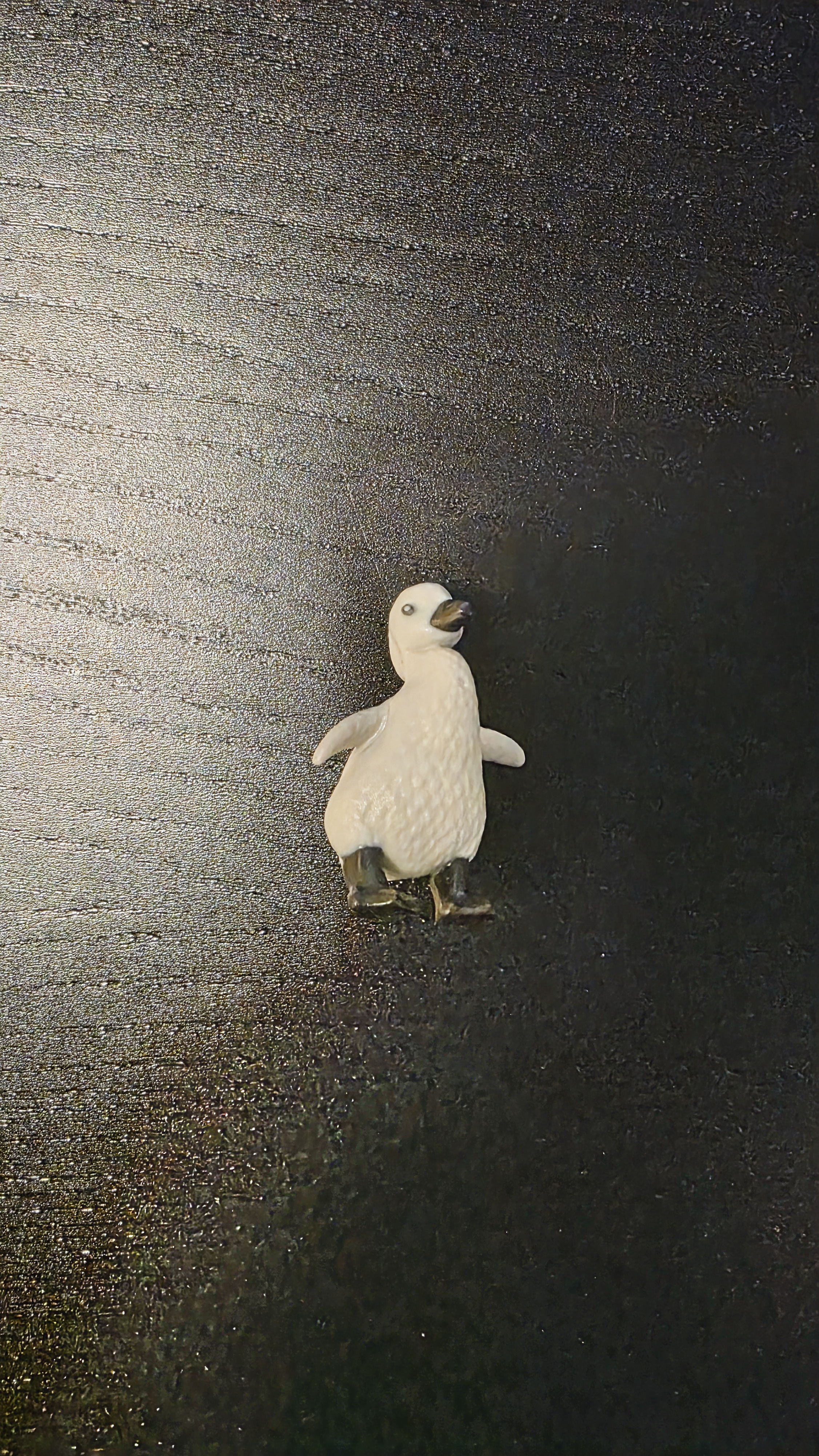어두운 배경 위 덩그러니 서 있는 펭귄 피규어